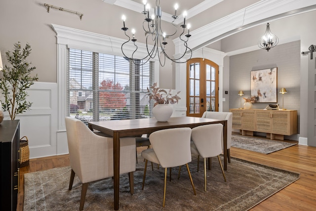 dining area featuring hardwood / wood-style flooring, a chandelier, crown molding, and french doors