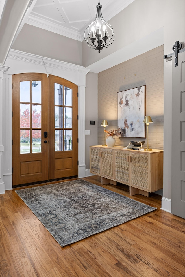 entrance foyer with a chandelier, wood-type flooring, a barn door, and french doors