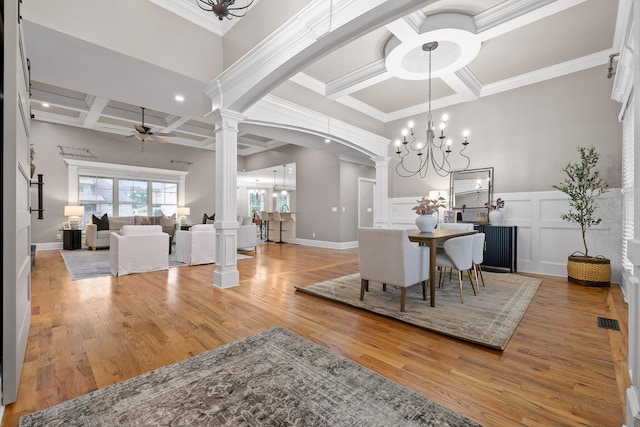 dining space featuring hardwood / wood-style floors, ceiling fan with notable chandelier, decorative columns, and crown molding