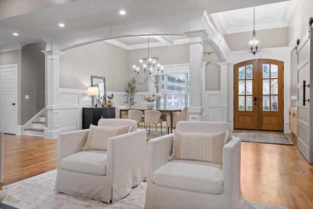 interior space featuring a notable chandelier, light hardwood / wood-style floors, ornamental molding, and french doors