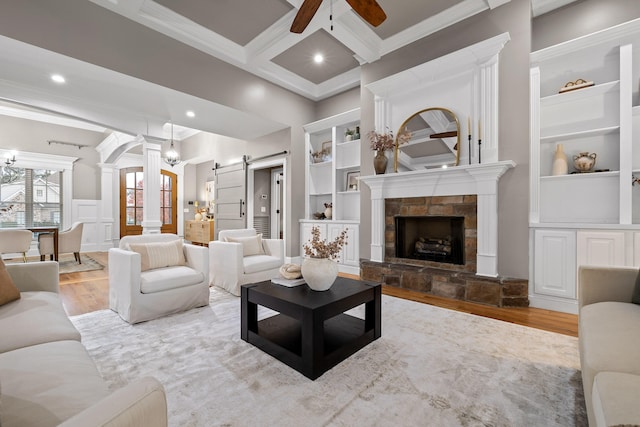 living room with ceiling fan, a barn door, light hardwood / wood-style floors, and coffered ceiling