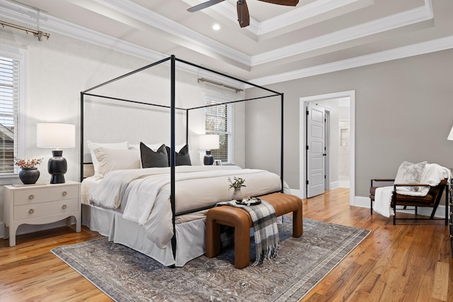 bedroom featuring a raised ceiling, crown molding, light hardwood / wood-style flooring, and ceiling fan