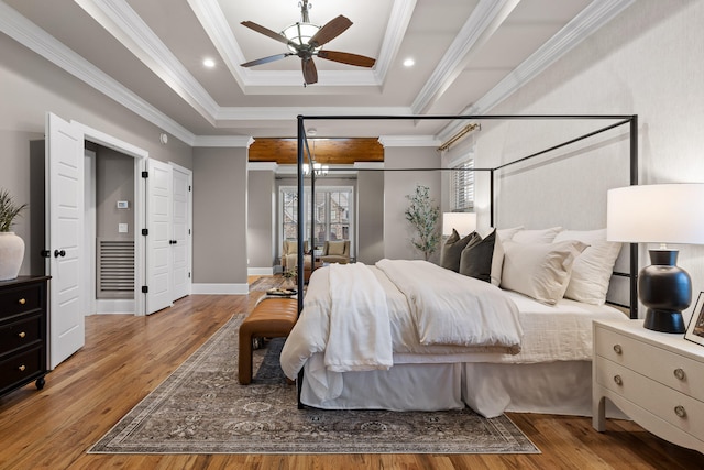 bedroom with hardwood / wood-style floors, a tray ceiling, ceiling fan, and crown molding