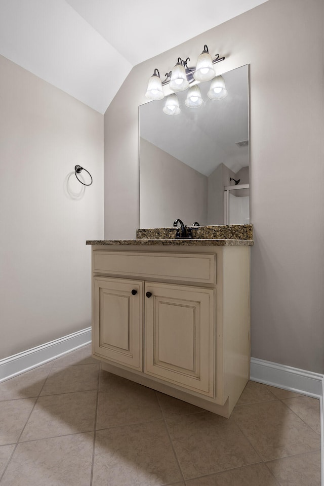 bathroom featuring tile patterned floors, vanity, and vaulted ceiling