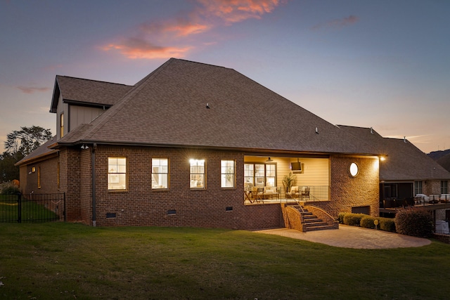 back house at dusk featuring a lawn