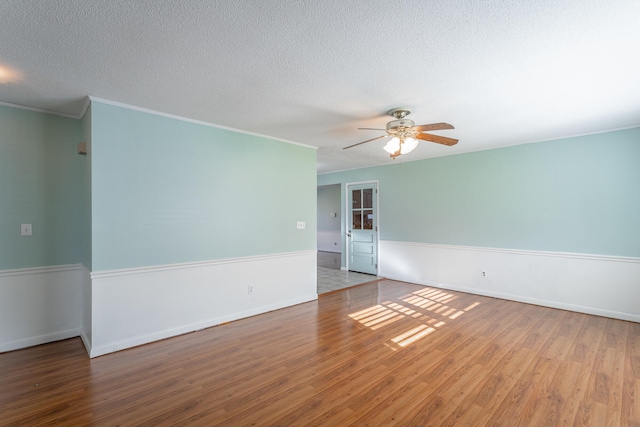 unfurnished room featuring ceiling fan, wood-type flooring, a textured ceiling, and ornamental molding