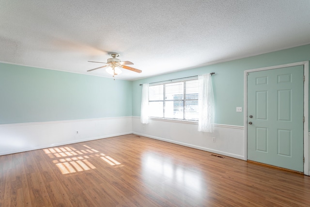 empty room with ceiling fan, wood-type flooring, and a textured ceiling