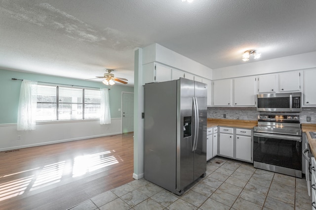 kitchen featuring decorative backsplash, appliances with stainless steel finishes, a textured ceiling, light hardwood / wood-style flooring, and white cabinetry