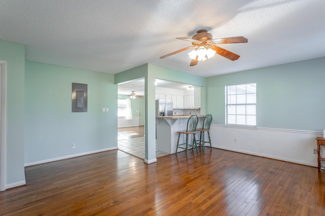 living room with ceiling fan, dark hardwood / wood-style flooring, and a textured ceiling