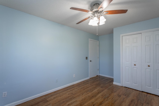 unfurnished bedroom featuring ceiling fan, a closet, dark wood-type flooring, and a textured ceiling