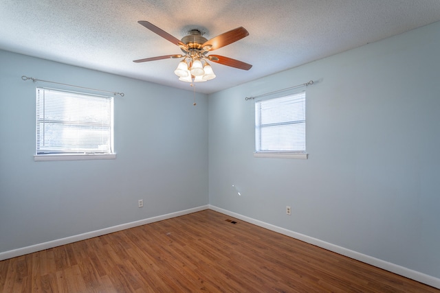 unfurnished room featuring ceiling fan, a healthy amount of sunlight, a textured ceiling, and hardwood / wood-style flooring