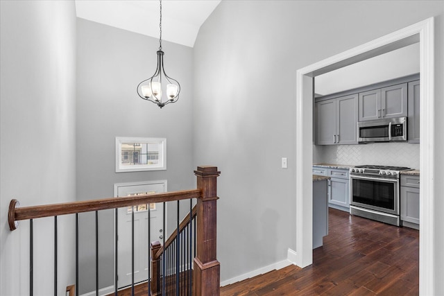 corridor with a notable chandelier, dark hardwood / wood-style flooring, and vaulted ceiling