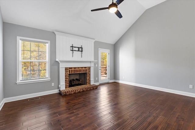 unfurnished living room with plenty of natural light, dark hardwood / wood-style floors, lofted ceiling, and a brick fireplace