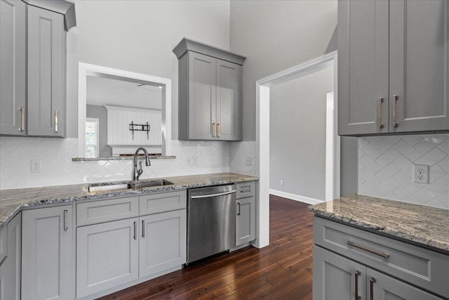 kitchen featuring gray cabinetry, backsplash, sink, stainless steel dishwasher, and dark hardwood / wood-style floors