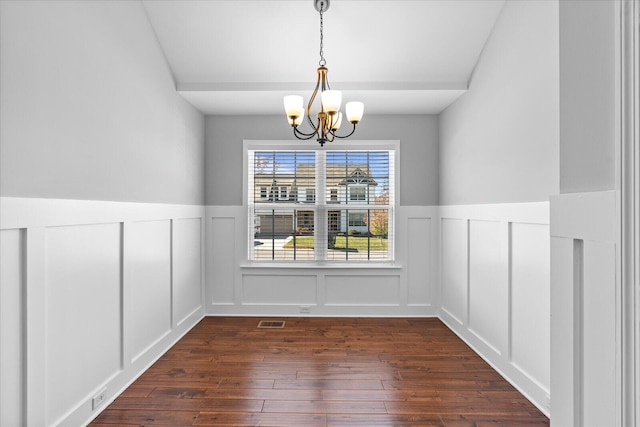 unfurnished dining area with a notable chandelier and dark hardwood / wood-style flooring