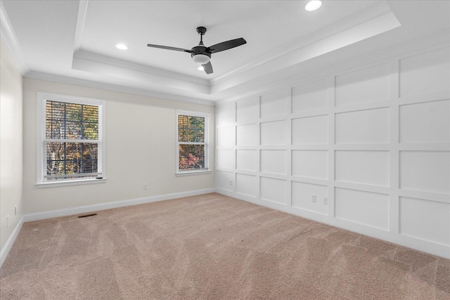 spare room featuring a tray ceiling, crown molding, ceiling fan, and light colored carpet