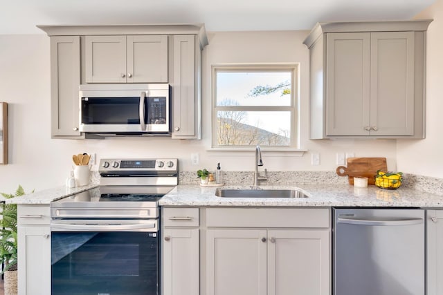 kitchen featuring sink, gray cabinets, stainless steel appliances, and light stone countertops