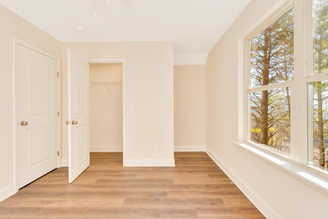 unfurnished bedroom featuring a walk in closet, light hardwood / wood-style floors, and a closet