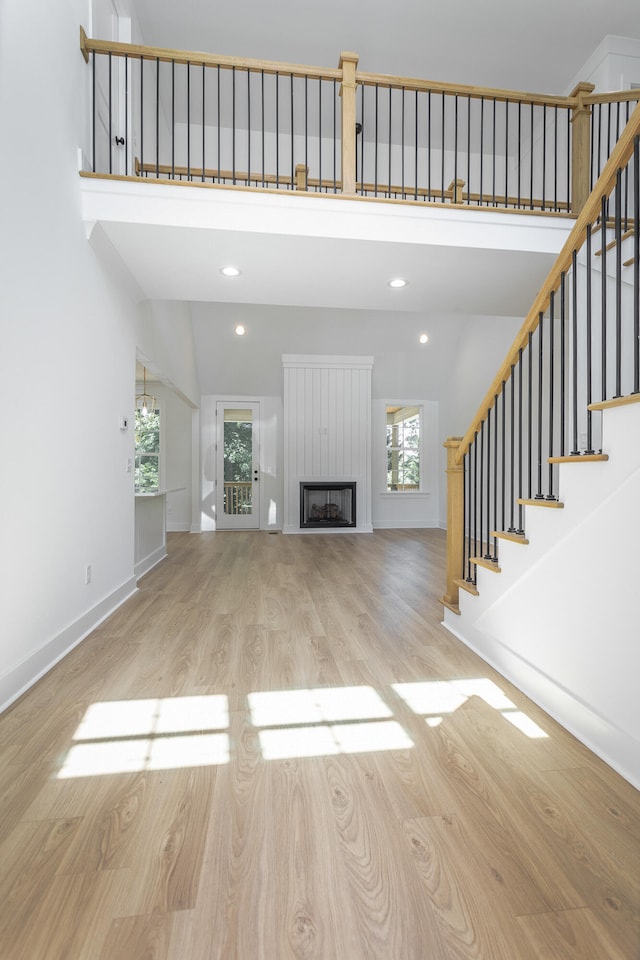 unfurnished living room with light wood-type flooring, vaulted ceiling, and plenty of natural light