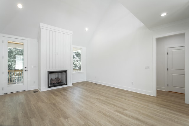 unfurnished living room featuring a fireplace, light hardwood / wood-style flooring, and vaulted ceiling