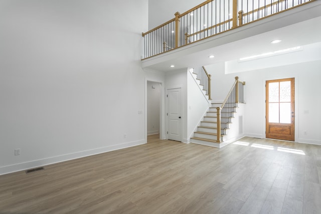 unfurnished living room with hardwood / wood-style flooring and a high ceiling