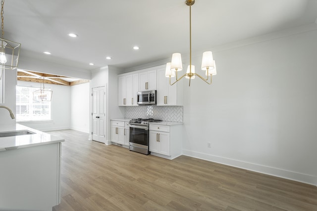 kitchen featuring light hardwood / wood-style flooring, white cabinets, decorative light fixtures, and appliances with stainless steel finishes