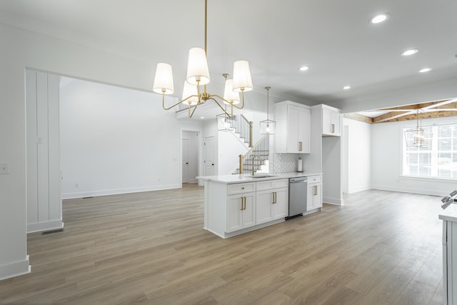 kitchen featuring white cabinets, decorative light fixtures, stainless steel dishwasher, and light hardwood / wood-style floors