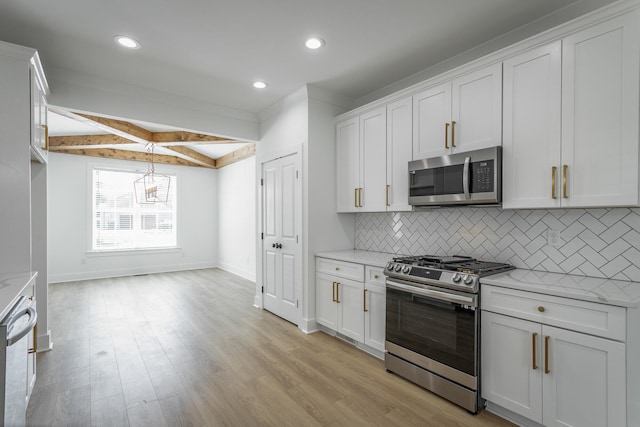 kitchen with appliances with stainless steel finishes, light hardwood / wood-style floors, white cabinetry, and beam ceiling