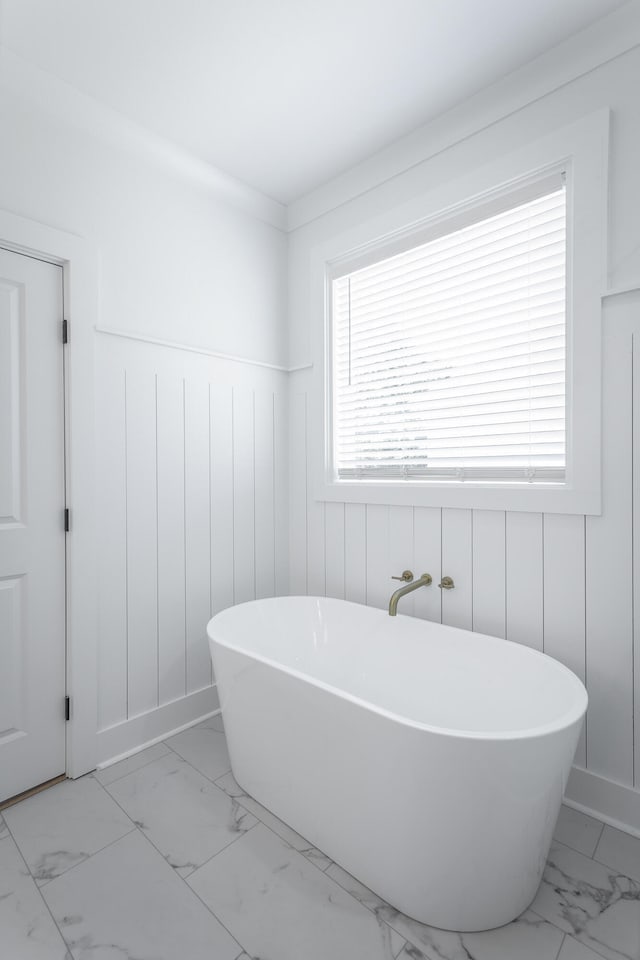 bathroom with a bathing tub and a healthy amount of sunlight