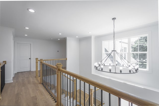 corridor featuring ornamental molding, a notable chandelier, and hardwood / wood-style flooring