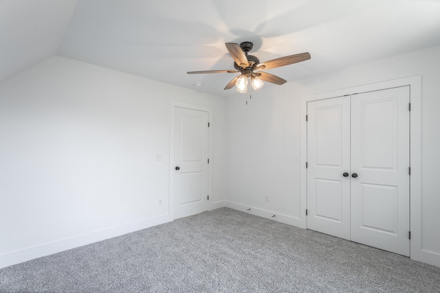 unfurnished bedroom featuring carpet floors, a closet, vaulted ceiling, and ceiling fan