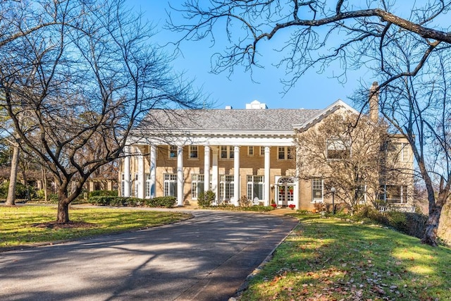 view of front of home with driveway, a chimney, and a front lawn