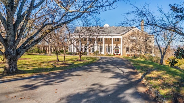 greek revival inspired property with driveway and a front lawn