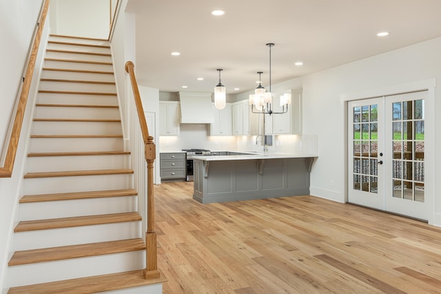 kitchen featuring french doors, white cabinets, decorative light fixtures, and light wood-type flooring