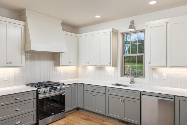 kitchen featuring appliances with stainless steel finishes, sink, light hardwood / wood-style flooring, white cabinets, and gray cabinets