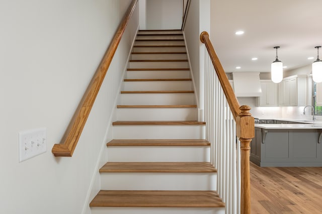 stairway with hardwood / wood-style floors and sink