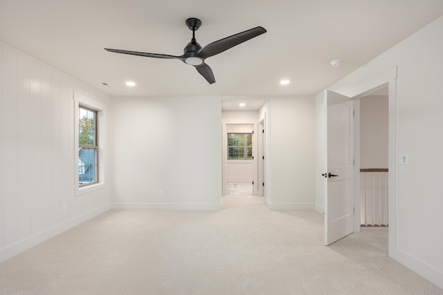 carpeted empty room featuring ceiling fan and wood walls