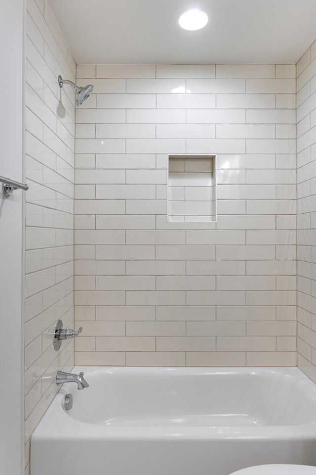 bathroom featuring toilet and tiled shower / bath