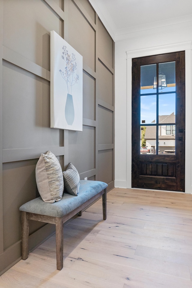 entryway with a chandelier, crown molding, and light hardwood / wood-style floors