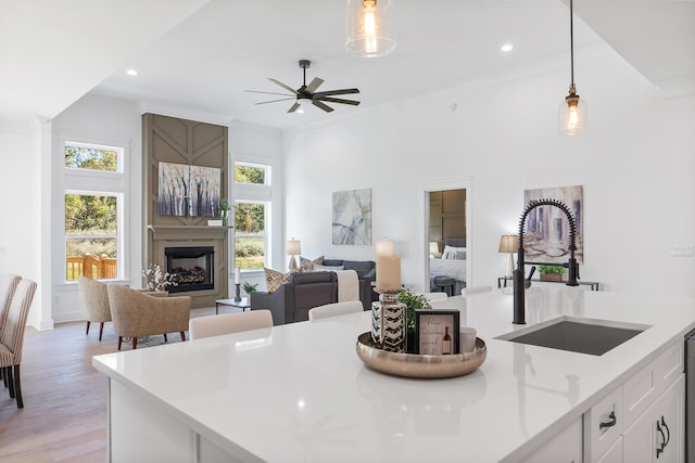 kitchen featuring white cabinetry, sink, ceiling fan, decorative light fixtures, and light wood-type flooring