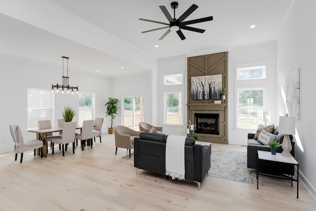 living room with ceiling fan with notable chandelier, light hardwood / wood-style flooring, and crown molding