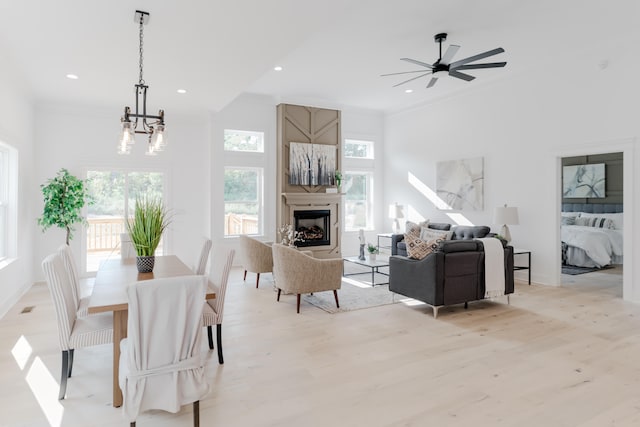 dining room with ornamental molding, ceiling fan with notable chandelier, and light wood-type flooring