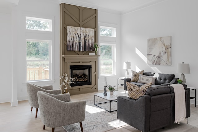 living room featuring crown molding, plenty of natural light, and light wood-type flooring