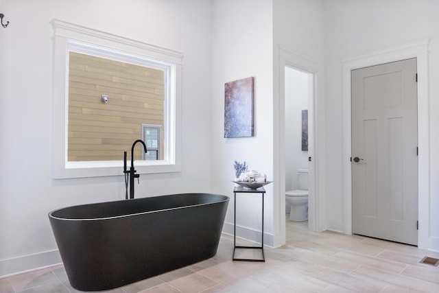 bathroom with a washtub, hardwood / wood-style flooring, and toilet