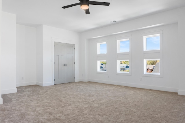 carpeted spare room featuring ceiling fan