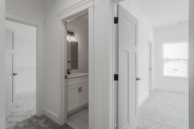 corridor with light colored carpet and sink