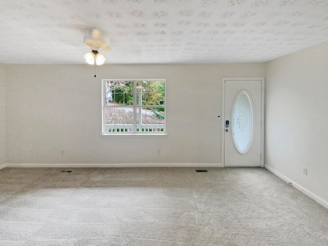 carpeted entryway featuring ceiling fan and a textured ceiling