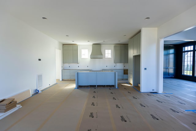 kitchen with wall chimney exhaust hood and a healthy amount of sunlight