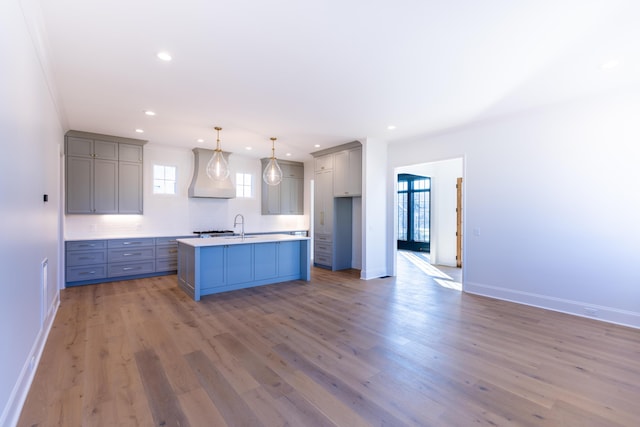 kitchen with light wood-style flooring, custom exhaust hood, and gray cabinets