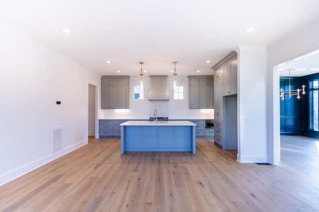 kitchen featuring gray cabinets, custom range hood, a sink, and visible vents